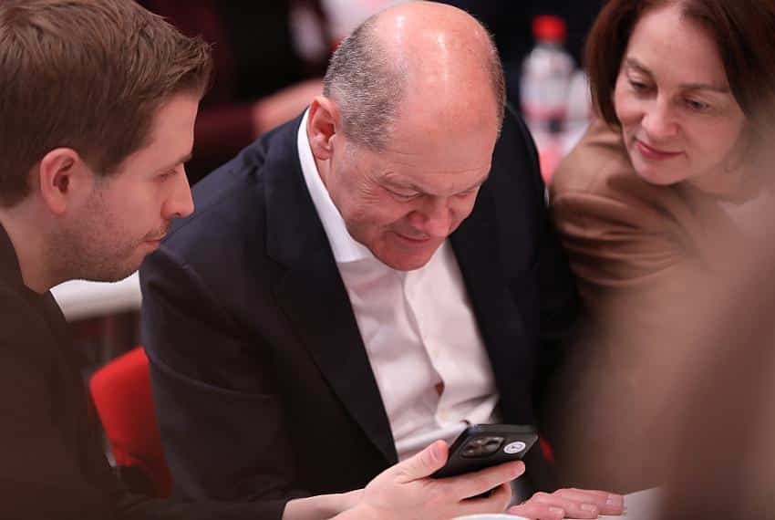 Kevin Kühnert, Olaf Scholz und Katarina Barley schauen auf ein Smartphone (Archiv)
